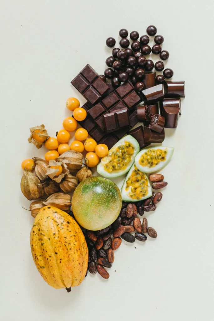 Cacao pod, dark chocolate, passion fruit and physalis arranged on a pale background, commercial food photograph